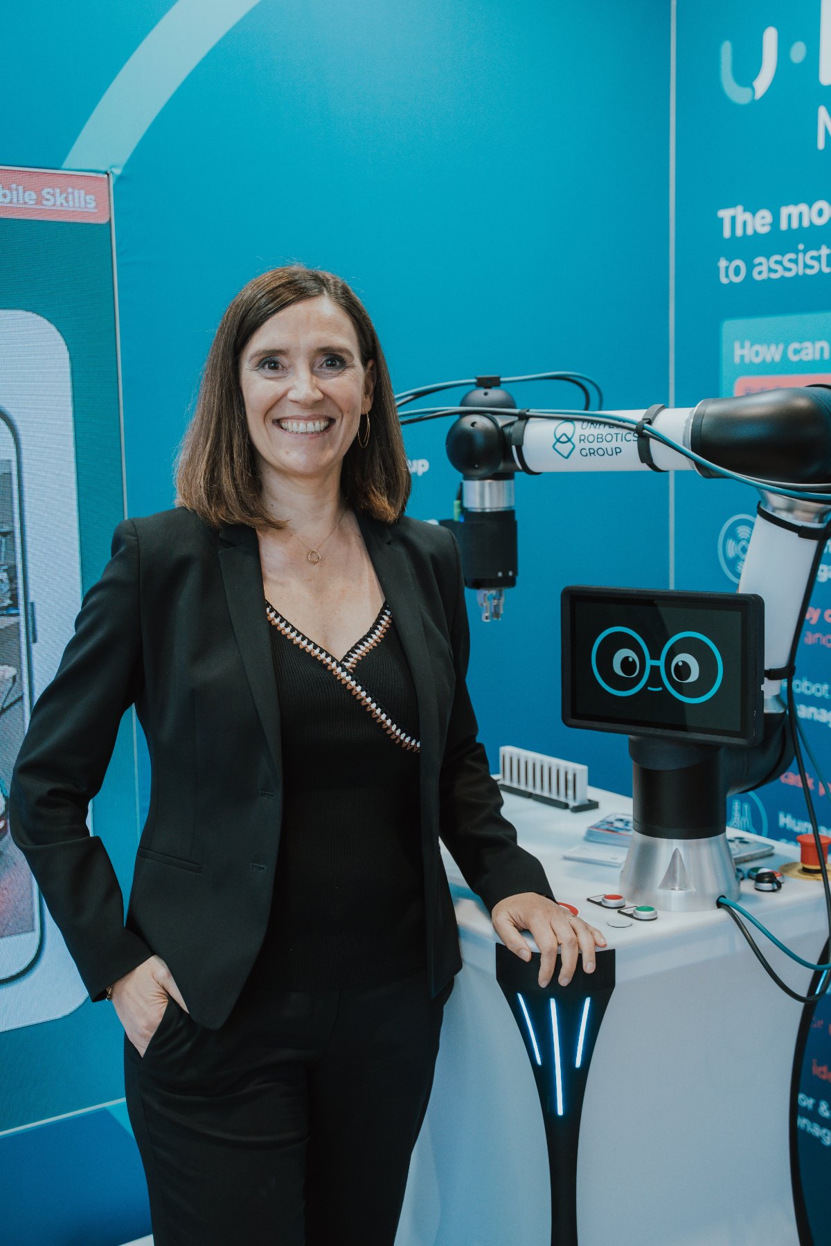 Kerstin Wagner at the United Robotics Group trade fair stand, next to uLab Mobile.
