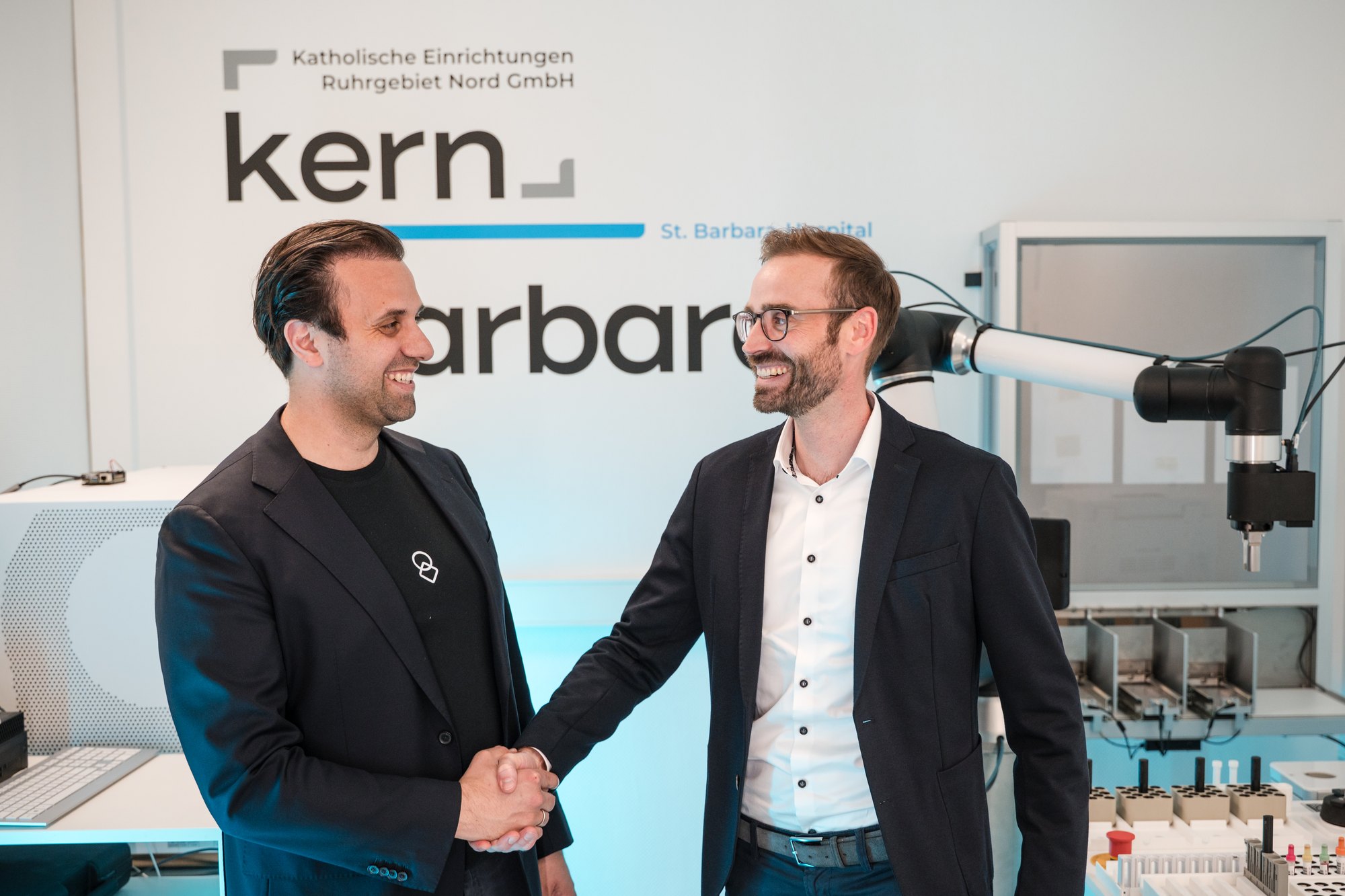 Handschlag zur Technologiepartnerschaft von United Robotics Group und KERN im Labor des St. Barbara-Hospitals Gladbeck