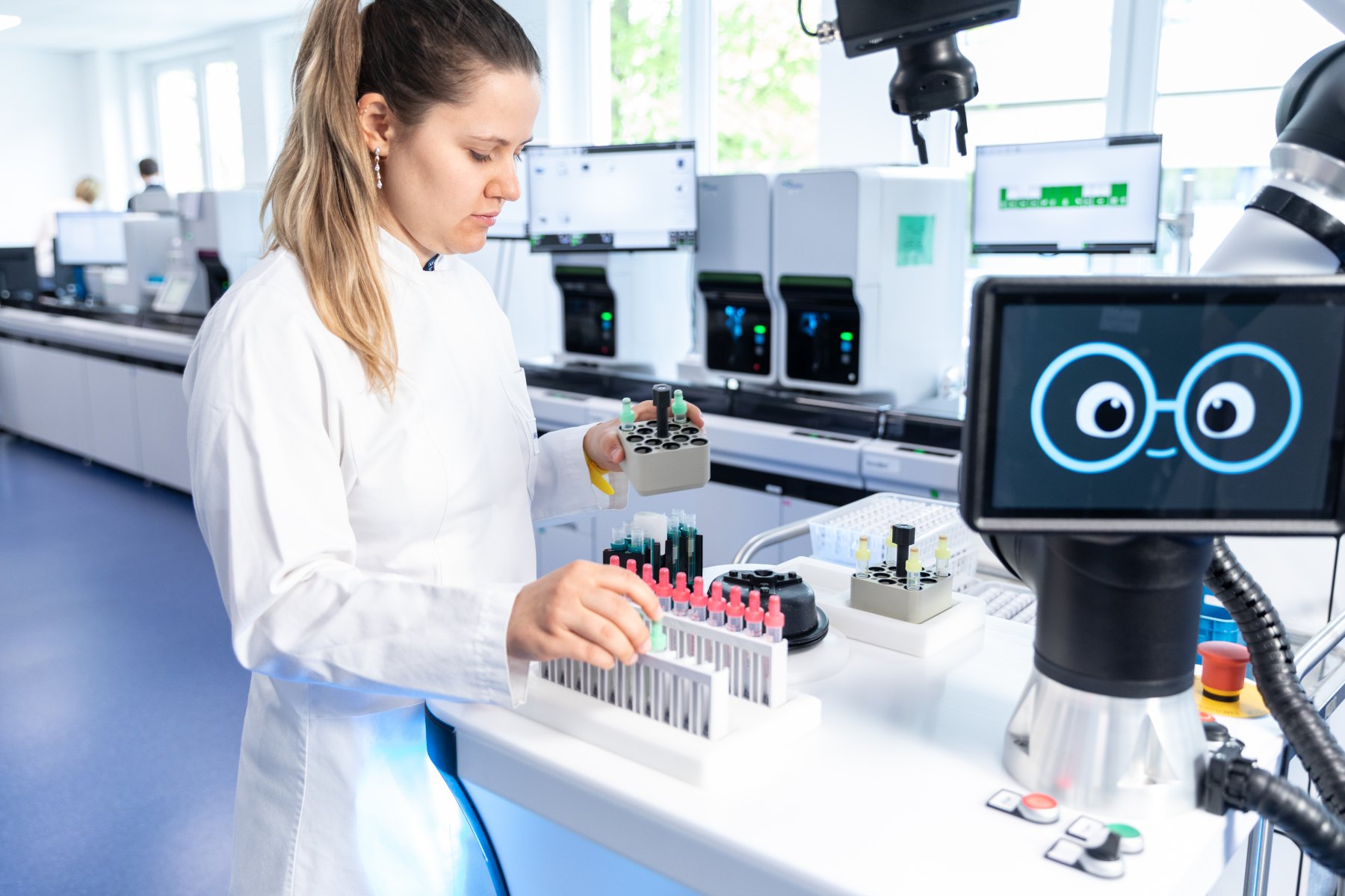 uLab Mobile handling samples: a laboratory employee sorts sample tubes while the robot arm works in parallel.